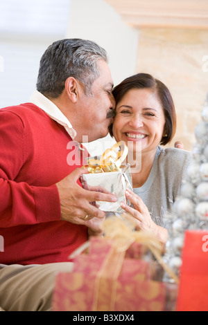 Middle Aged Couple Affectionately Sitting And Holding Christmas Present Stock Photo