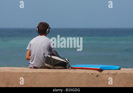 Spanish teenage surfer wearing headphones and waiting for waves at La Cicer, Playa de Las Canteras, Las Palmas, Gran Canaria. Stock Photo