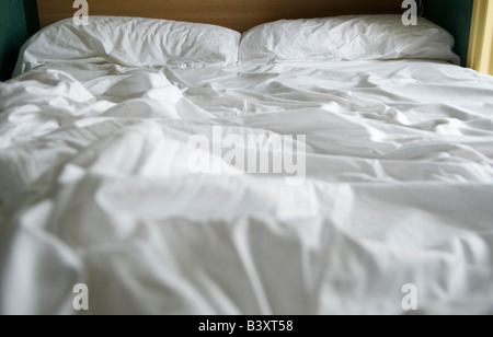 Unmade bed white bed sheets crumpled rumpled HOMER SYKES Stock Photo