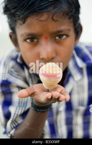 Indian boy smiling playing with wooden spinning top toy. India Stock Photo