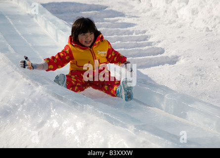 Sapporo Japan Sapporo Snow Festival Odori Park toddler enjoys a ride on a carved snow slide Stock Photo