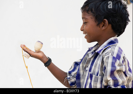Indian boy smiling playing with wooden spinning top toy. India Stock Photo