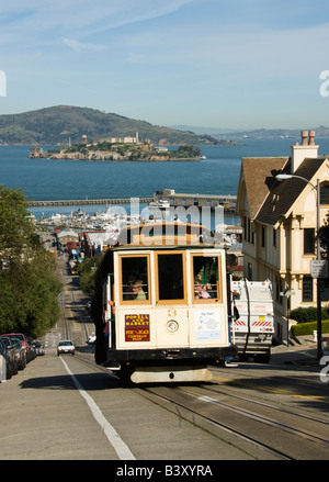 A Cable Car in San Francisco California climbs Hyde Street with Alcatraz in the background Stock Photo