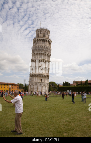 Old man posing for photo of him holding up the Leaning tower in Campo di Miracoli field of Miracles Pisa Tuscany Italy Stock Photo