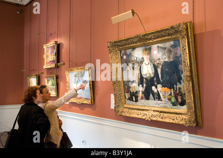 Visitors to the Courtauld Gallery looking at A Bar at the Folies Bergère by Edouard Manet, London, England, UK Stock Photo
