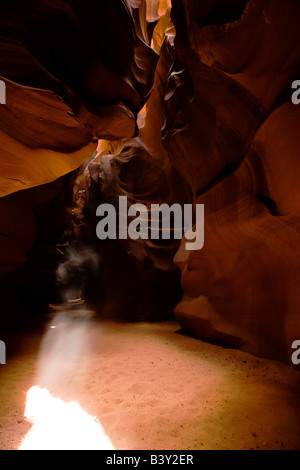 Streaming light beams, shaft of sunlight shining through to inside upper Antelope Canyon, illuminating patterns in red eroded sandstone walls Arizona Stock Photo