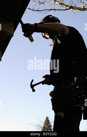 Man with hammer and chisel fixing roof Stock Photo