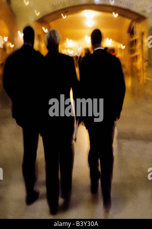 New York City. Rear view of three full figure businessmen, in business attire, walking indoors through Grand Central Station. Stock Photo