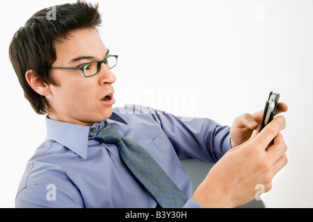 Asian businessman with surprised expression looking at message on his pda cellphone Stock Photo