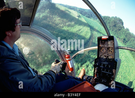Helicopter crop dusting hilly terrain at low altitude in western Pennsylvania, USA Stock Photo