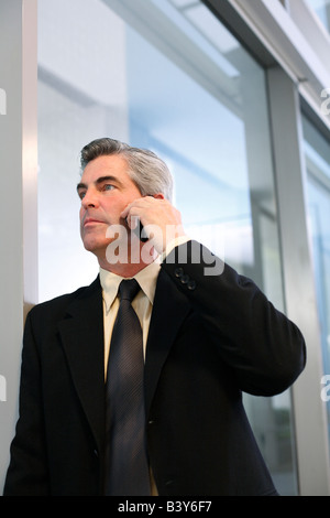 Executive using mobile phone and staring out window in Chicago office building Stock Photo