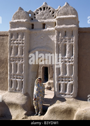 Sudan, Sahara Desert, Qubbat Selim. A Nubian girl stand in an archway at the village of Qubbat Selim. Traditional Nubian architecture. Traditional Nubian architecture and plasterwork of a fine archway to a house and its courtyard at Qubbat Selim. Stock Photo