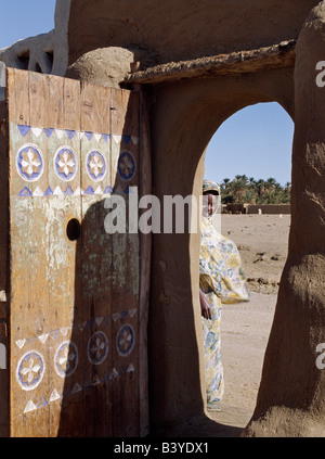 Sudan, Sahara Desert, Qubbat Selim. A finely carved painted door graces the arched entrance to a house compound at Qubbat Selim. This village, situated close to the River Nile in Northern Sudan, still retains much of its traditional architecture, plasterwork and decoration.. Stock Photo