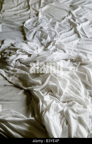 Crumpled frowzled bed sheets an unmade bed white bed sheets slept on. HOMER SYKES Stock Photo