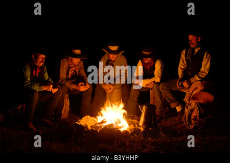 USA, Oregon, Seneca, Ponderosa Ranch. Five cowboys sitting around a nighttime campfire. (MR) (PR) Stock Photo