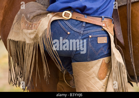 USA, Oregon, Seneca, Ponderosa Ranch. View of a cowboy's backside as he mounts his horse. (MR) (PR) Stock Photo