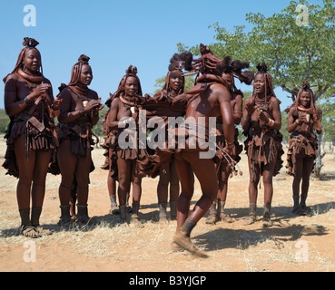 Namibia, Kaokoland. Himba women perform the otjiunda dance, stamping their feet, clapping and chanting in a circle. Their bodies Stock Photo