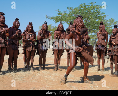 Namibia, Kaokoland. Himba women perform the otjiunda dance, stamping their feet, clapping and chanting in a circle. Their bodies Stock Photo