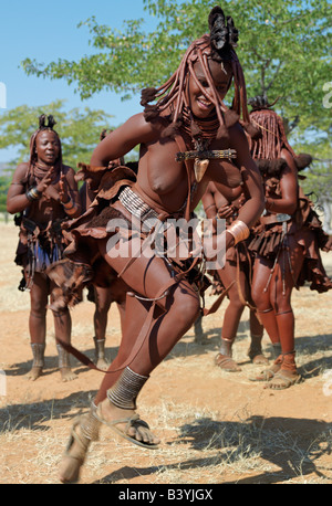 Namibia, Kaokoland. Himba women perform the otjiunda dance, stamping their feet, clapping and chanting while one of them gyrates Stock Photo