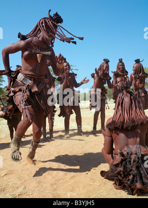 Namibia, Kaokoland. Himba women perform the otjiunda dance, stamping their feet, clapping and chanting while one of them gyrates Stock Photo