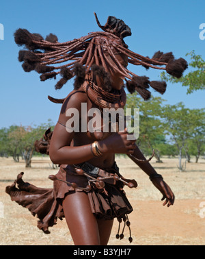 Namibia, Kaokoland. Himba women perform the otjiunda dance, stamping their feet, clapping and chanting while one of them gyrates Stock Photo