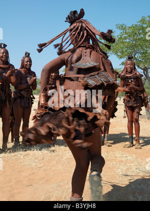 Namibia, Kaokoland. Himba women perform the otjiunda dance, stamping their feet, clapping and chanting while one of them gyrates Stock Photo