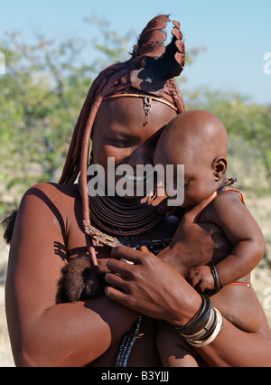 Namibia, Kaokoland. A Himba mother and child. Their bodies gleam from a mixture of red ochre, butterfat and herbs. The woman's l Stock Photo