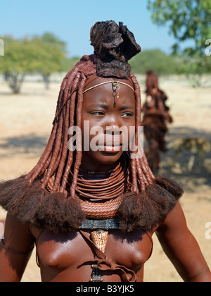 Namibia, Kaokoland. An attractive Himba woman in traditional attire. Her body gleams from a mixture of red ochre, butterfat and Stock Photo