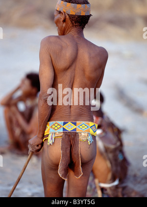 Namibia, Eastern Bushmanland, Tsumkwe. An old !Kung man, his skin shrivelled with age, watches the singing and dancing of his fr Stock Photo