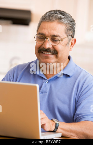Man in kitchen with laptop smiling Stock Photo