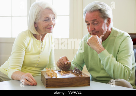 Couple playing chess in living room smiling Stock Photo
