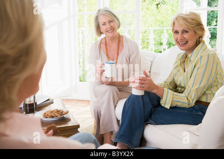 Three women in living room with coffee smiling Stock Photo