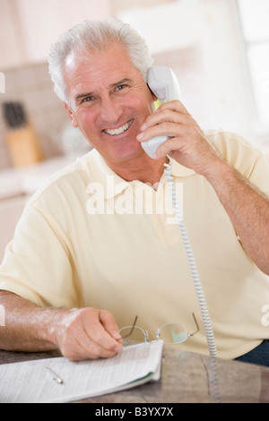 Man in kitchen on telephone smiling Stock Photo