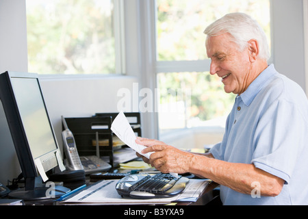 Man in home office with computer and paperwork smiling Stock Photo