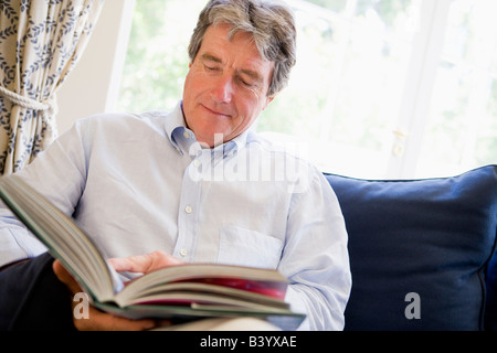 Man relaxing with book in living room Stock Photo