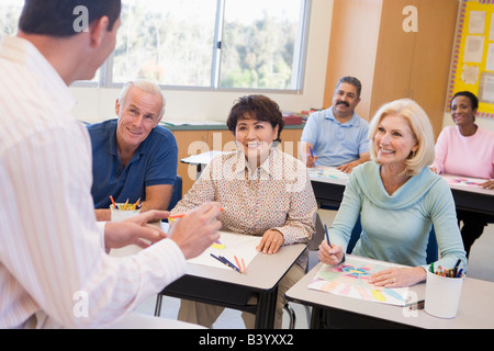 Adult students in class drawing pictures with teacher in foreground (selective focus) Stock Photo