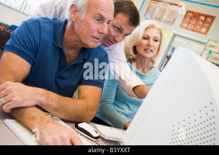 Three people at computer terminal Stock Photo