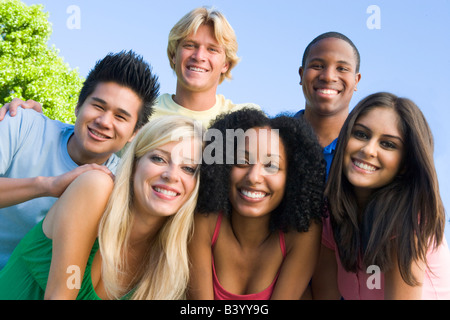 Six people outdoors huddling over camera Stock Photo