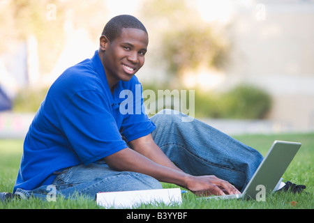 Man outdoors sitting on grass with laptop (selective focus) Stock Photo