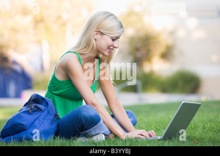 Woman outdoors sitting on grass with laptop (selective focus) Stock Photo