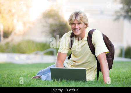 Man outdoors sitting on grass with laptop (selective focus) Stock Photo