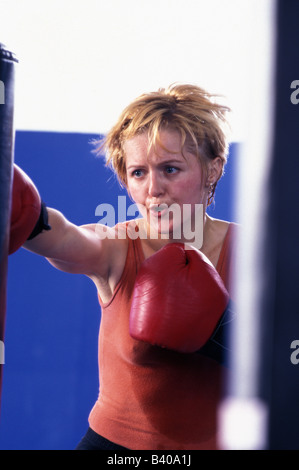 Woman working out with heavy punching bag Stock Photo