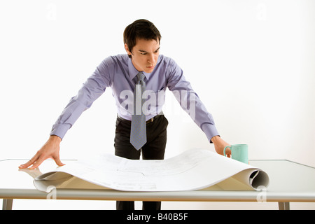 Asian business man standing looking over blueprints Stock Photo