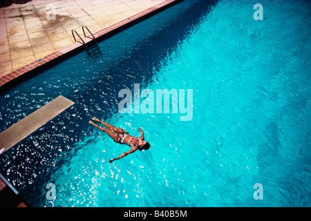 Woman floats in a clear blue swimming pool Stock Photo