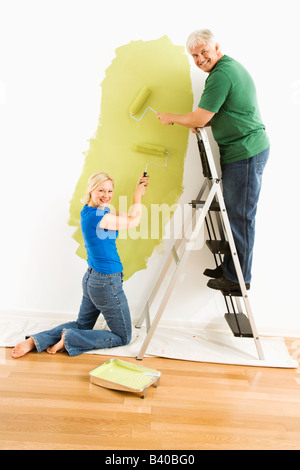 Middle aged couple painting wall green and looking at viewer Stock Photo