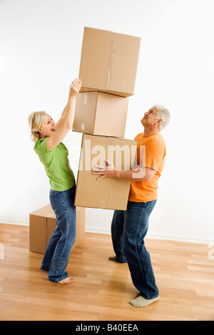 Middle aged couple with stack of cardboard moving boxes. Stock Photo