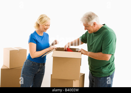 Middle aged couple packing or unpacking moving boxes Stock Photo