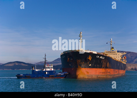 A tug assists a bulk carrier as it arrives in port. Stock Photo