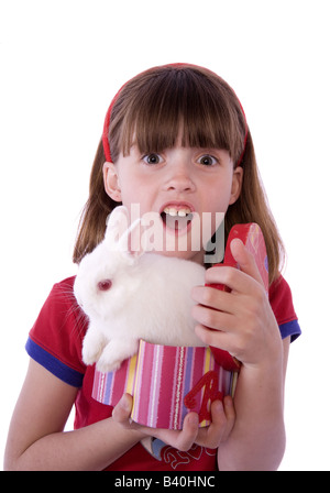 Surprised girl with white bunny rabbit coming out of gift box isolated in white Stock Photo