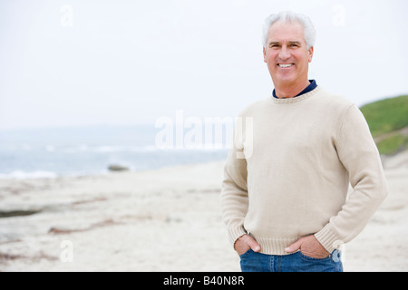 Man at the beach with hands in pockets smiling Stock Photo